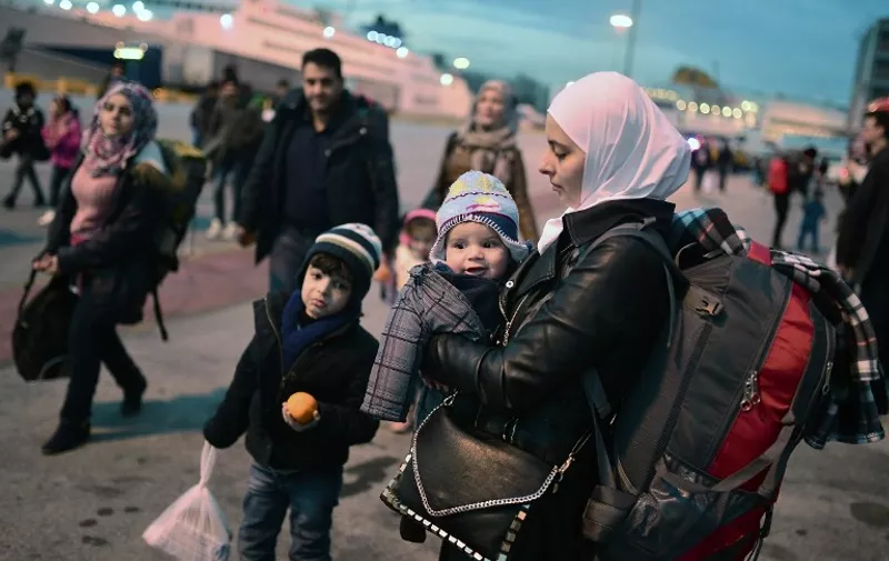 A migrant mother with her children arrives to the port of Piraeus in Athens area along with other migrants from the Greek Islands of Lesbos and Chios  on February 18, 2016. 
Greece on February 18, 2016 hit back at European Union criticism of its handling of the massive migrant influx, saying the time for blaming Athens was "over" as it prepared to open new centres to register refugees. / AFP / LOUISA GOULIAMAKI
