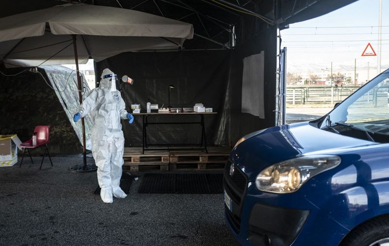 A military medical worker guides a driver on January 12, 2021 going through a drive-in swab testing centre for COVID-19 set up by the Italian Army on the parking lot of the Juventus stadium in Turin, during the pandemic caused by the novel coronavirus. - Italy has been one of the countries worst hit by the Covid-19 pandemic, with more than 75,000 deaths so far. (Photo by Marco Bertorello / AFP)