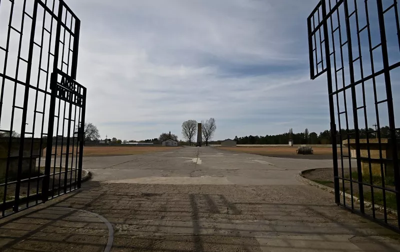 (FILES) A view through the open gate of the former Nazi concentration camp of Sachsenhausen is seen in Oranienburg on April 16, 2020 amid the novel coronavirus pandemic. German prosecutors said on September 1, 2023 they have charged a former SS guard, now 98 years old, for complicity in the killings of over 3,300 people at a Nazi concentration camp during World War II. The German man, unnamed by prosecutors, was an adolescent when he worked as a SS watchman at the Sachsenhausen camp between July 1943 and February 1945. He is accused of "having assisted in the cruel and insidious killing of thousands of prisoners" in the camp, said prosecutor Thomas Hauburger. A psychiatric assessment in October 2022 of the suspect has found that he is fit to stand trial within certain limits. Given his young age at the time of the alleged crime, a juvenile court will decide whether to open proceedings. (Photo by Tobias SCHWARZ / AFP)