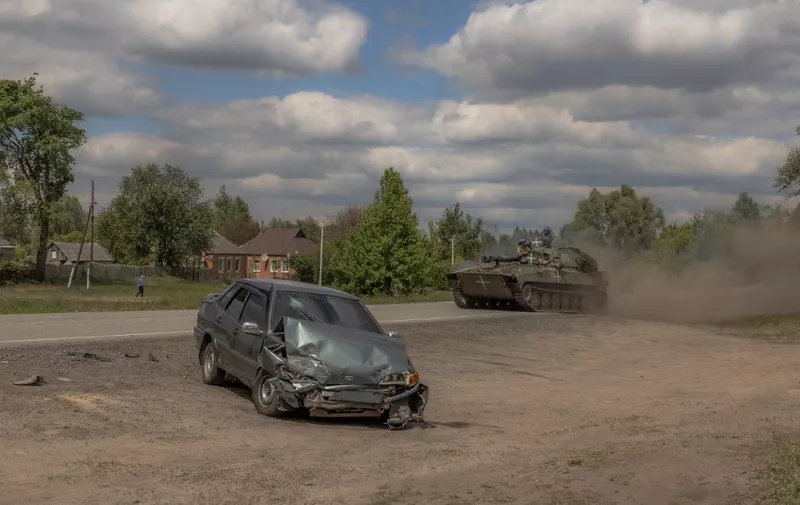 A Ukrainian self-propelled howitzer 2S1 Gvozdika drives past a damaged car on a road in the Vovchansk district, Kharkiv region, on May 12, 2024, amid the Russian invasion of Ukraine. Thousands of people have been evacuated from border areas in Ukraine's Kharkiv region, as Russia kept up constant strikes on a key town as part of a cross-border offensive, officials said on May 12, 2024. The surprise Russian attack across Ukraine's northeastern border began on Friday, with troops making small advances in an area from where they had been pushed back nearly two years ago. (Photo by Roman PILIPEY / AFP)