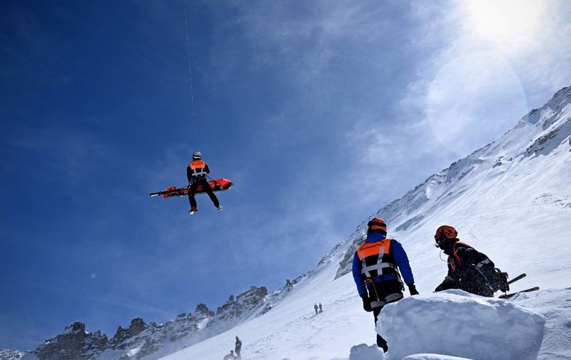 An helicopter of the French "Peloton de Gendarmerie de Haute Montagne" (High Mountain Police Squad, PGHM) evacuates a volunteer, acting as an injured person, during an avalanche search and rescue training, near Briancon in the French Alps on March 16, 2023. (Photo by Nicolas TUCAT / AFP)