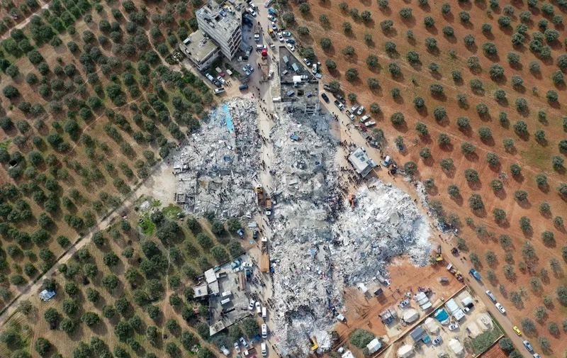 This aerial view shows residents searching for victims and survivors amidst the rubble of collapsed buildings following an earthquake in the village of Besnia near the twon of Harim, in Syria's rebel-held noryhwestern Idlib province on the border with Turkey, on February 6, 2022. - Hundreds have been reportedly killed in north Syria after a 7.8-magnitude earthquake that originated in Turkey and was felt across neighbouring countries. (Photo by Omar HAJ KADOUR / AFP)