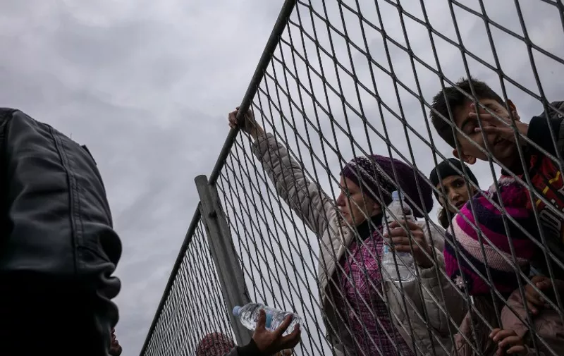 A women passes water bottles over a gate to her relatives on September 22, 2015 from inside the Opatovac transit center for migrants and refugees, where women and children had priority access and men were still waiting outside. Croatian Prime Minister Zoran Milanovic urged Serbia on September 22 to restart directing migrants to Hungary and Romania to help ease the burden on his own country. AFP PHOTO / FEDERICO SCOPPA