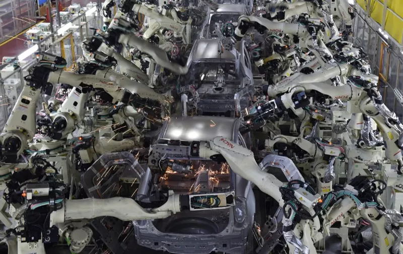 A general view shows the body welding workshop which uses automated welding machine robots that assemble automobile bodies called white body (body before painting) at Toyota Motor's Tsutsumi plant in Toyota, Aichi prefecture on December 4, 2014.  AFP PHOTO / KAZUHIRO NOGI