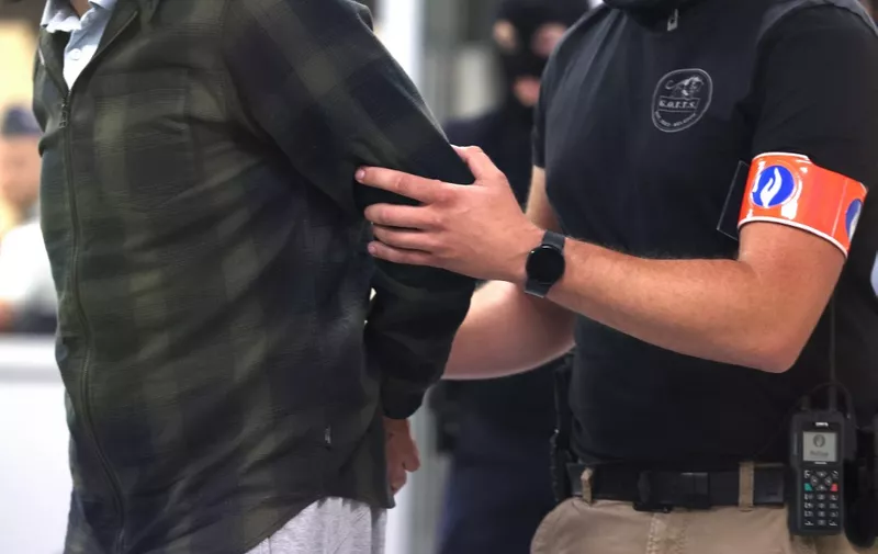 One of the accused is led into the courtroom by special police during the trial of alleged jihadists accused of directing or aiding suicide bombings in Brussels' metro and airport on March 22, 2016, at the Justitia building in Brussels, on July 6, 2023. (Photo by Geert Vanden Wijngaert / POOL / AFP)