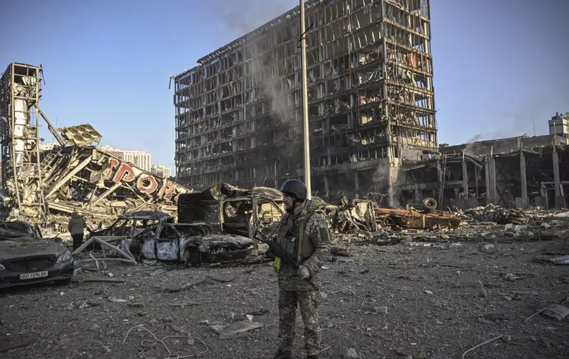 A Ukranian serviceman walks between debris of Retroville shopping mall and residential district after a Russian attack in Kyiv on March 21, 2022. - At least six people were killed in the overnight bombing of a shopping centre in the Ukrainian capital Kyiv, an AFP journalist said, with rescuers combing the wreckage for other victims. (Photo by ARIS MESSINIS / AFP)