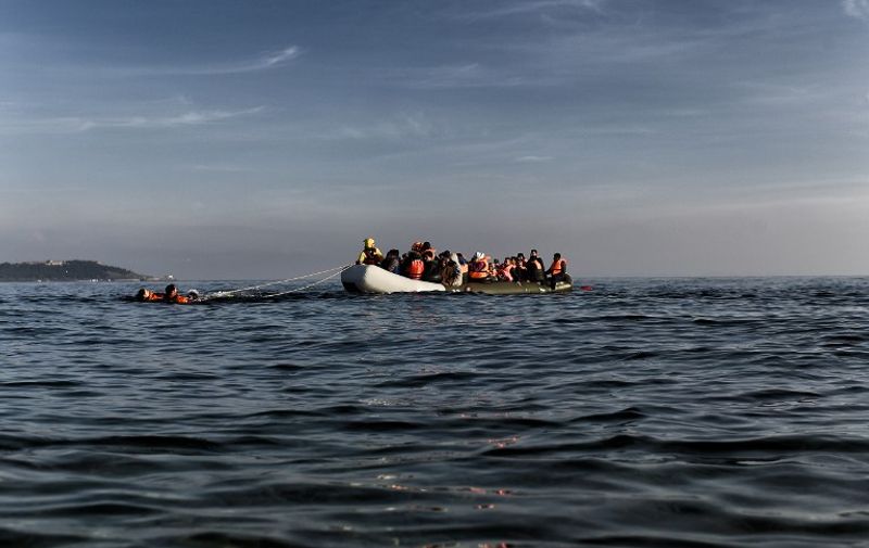 Migrants arrive on a rubber boat in Mytilene, on the Greek island of Lesbos, after crossing the Aegean sea from Turkey, on February 28, 2016. / AFP / ARIS MESSINIS
