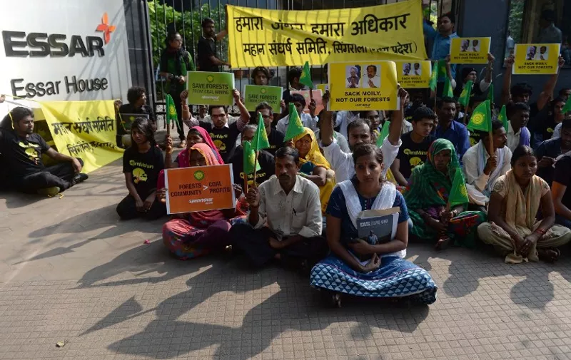Activists from the environmental group Greenpeace and local farmers from Madhya Pradesh state sit outside the headquarters of India's Essar Group, where a giant banner was unfurled on the facade of the building, during a protest in Mumbai on January 22, 2014. Activists protested against the proposed destruction of Mahan forests in Singrauli, Madhya Pradesh where Essar Power has been allotted a captive coal block. AFP PHOTO/ PUNIT PARANJPE