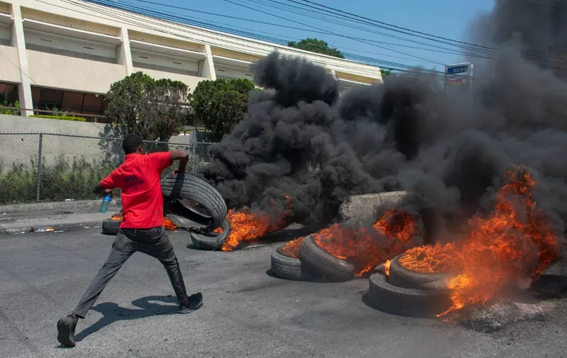 A protester burns tires during a demonstration following the resignation of its Prime Minister Ariel Henry, in Port-au-Prince, Haiti, on March 12, 2024. A political transition deal in Haiti marks a key step forward for the violence-ravaged country but far more needs to be done, with some experts warning the situation could deteriorate further. (Photo by Clarens SIFFROY / AFP)