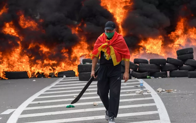 A man walks past burning tires at a barricade set up to block access roads to the historic city of Cetinje during a protest against the inauguration of the new head of the Serbian Orthodox Church on September 5, 2021 in Montenegro. - The new head of the Serbian Orthodox Church in Montenegro was inaugurated, arriving by helicopter under the protection of police who dispersed protesters with tear gas. The decision to anoint Bishop Joanikije as the new Metropolitan of Montenegro at the historic monastery of Cetinje has aggravated ethnic tension in the tiny Balkan state. (Photo by SAVO PRELEVIC / AFP)