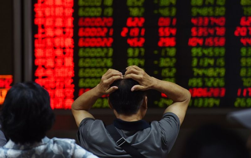 An investor looks at screens showing stock market movements at a securities company in Beijing on July 14, 2015. Hundreds of firms were expected to resume trading again on July 14, adding to the more than 400 that returned July 13, after they were suspended over the past few weeks to prevent a market meltdown. Authorities intervened after the Shanghai index plunged 30 percent in three weeks, wiping trillions of dollars from market capitalisations, spreading contagion in regional markets and raising fears over the potential impact to the real economy. AFP PHOTO / GREG BAKER