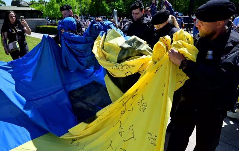 Police officers confiscate a giant Ukrainian flag that activists had unfurled at the Soviet War Memorial in Tiergarten in Berlin on May 8, 2022 during commemorations to mark the 77th anniversary of the 1945 victory against Nazi Germany. (Photo by John MACDOUGALL / AFP)