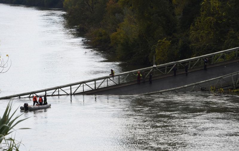 Rescuers sail near a suspension bridge which collapsed on November 18, 2019 in Mirepoix-sur-Tarn, near Toulouse, southwest France. - A 15-year-old girl was killed after a suspension bridge over a river collapsed on November 19, causing a car, a truck and possibly a third vehicle to plunge into the water, local authorities said. Four people were rescued but several others were feared missing after the collapse of the bridge linking the towns of Mirepoix-sur-Tarn and Bessieres, 30 kilometres (18 miles) north of the city of Toulouse, said fire service and local security chief Etienne Guyot. (Photo by ERIC CABANIS / AFP)
