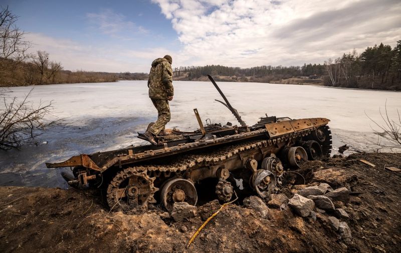 A Ukrainian serviceman stands near a destroyed Russian tank in the northeastern city of Trostyanets', on March 29, 2022. - Ukraine said on March 26, 2022 its forces had recaptured the town of Trostyanets, near the Russian border, one of the first towns to fall under Moscow's control in its month-long invasion. (Photo by FADEL SENNA / AFP)