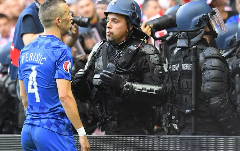 Croatia's midfielder Ivan Perisic speaks with a French riot police officer after flares were thrown onto the pitch during the Euro 2016 group D football match between Czech Republic and Croatia at the Geoffroy-Guichard stadium in Saint-Etienne on June 17, 2016. / AFP PHOTO / JEAN-PHILIPPE KSIAZEK