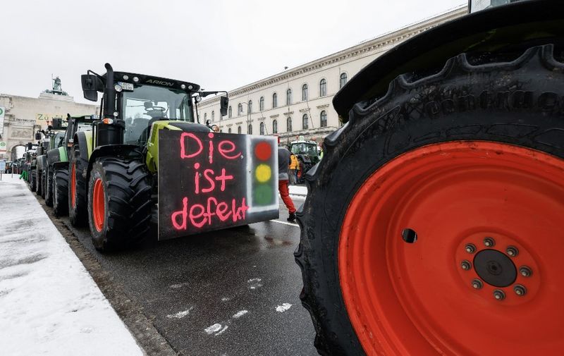 Farmers have attached a placard reading "The redlight is broken (refering to the "Ampel", meaning the coalition government)" on a tractor standing at Odeonsplatz square in the city center to take part in protests against the federal government's austerity plans in Munich, southern Germany, on January 8, 2024. The German government on January 4, 2024 had dropped part of its plans to cut agricultural subsidies in the face of massive protests from farmers. Contrary to the initial plans, a discount on the vehicle tax for agricultural machinery would be maintained, the government's spokesman said in a statement. (Photo by MICHAELA REHLE / AFP)