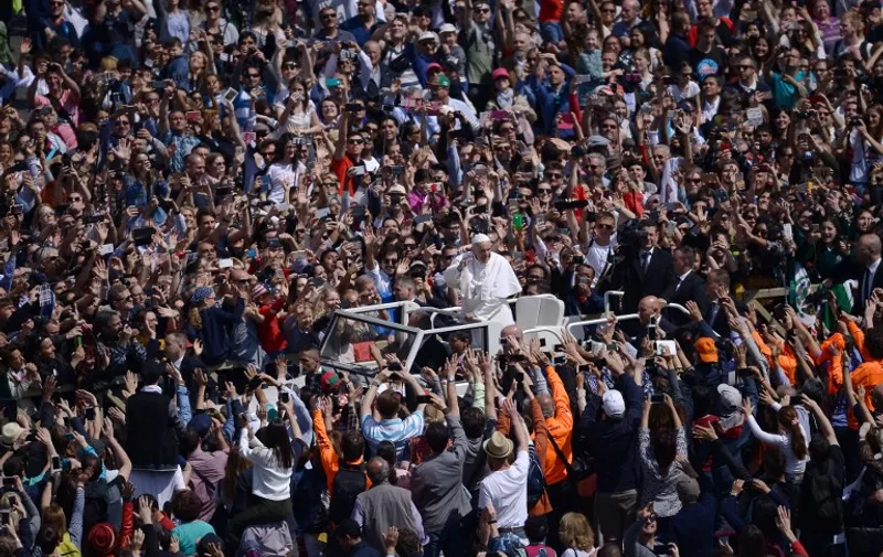 Pope Francis greets the crowd from the popemobile during the Easter Sunday mass on April 16, 2017 at St Peter's square in Vatican. Christians around the world are marking the Holy Week, commemorating the crucifixion of Jesus Christ, leading up to his resurrection on Easter. / AFP PHOTO / Filippo MONTEFORTE