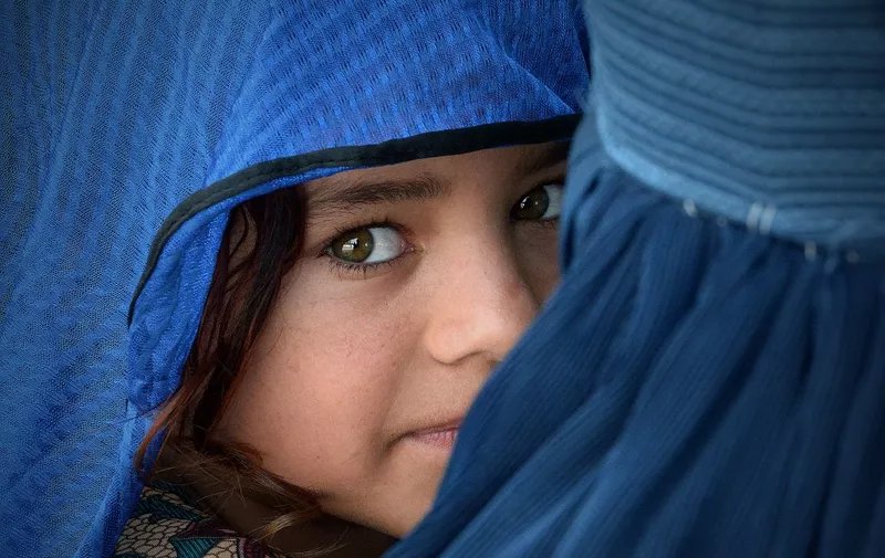 An Afghan woman carries her girl during the visit of the United Nations High Commissioner for Refugees, Filippo Grandi (unseen) at the Azakhel Voluntary Repatriation Centre in Nowshera on September 8, 2018. - The United Nations High Commissioner for Refugees Filippo Grandi is on an official three-day visit to Islamabad. (Photo by ABDUL MAJEED / AFP)