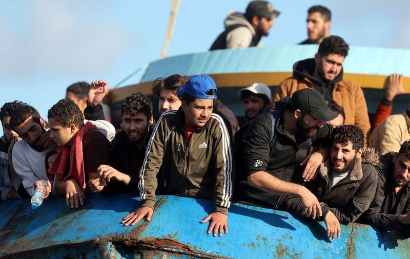Rescued refugees and migrants stand aboard a boat at the town of Paleochora, southwestern Crete island on November 22, 2022, following a rescue operation. (Photo by Costas METAXAKIS / AFP)