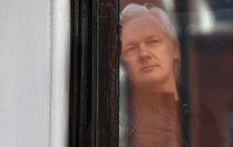 (FILES) In this file photo taken on May 19, 2017 Wikileaks founder Julian Assange look out from a window at the Embassy of Ecuador in London. - British police have arrested WikiLeaks founder Julian Assange at Ecuador's embassy in London after his asylum was withdrawn, the police said in a statement on April 11, 2019. (Photo by Justin TALLIS / AFP)