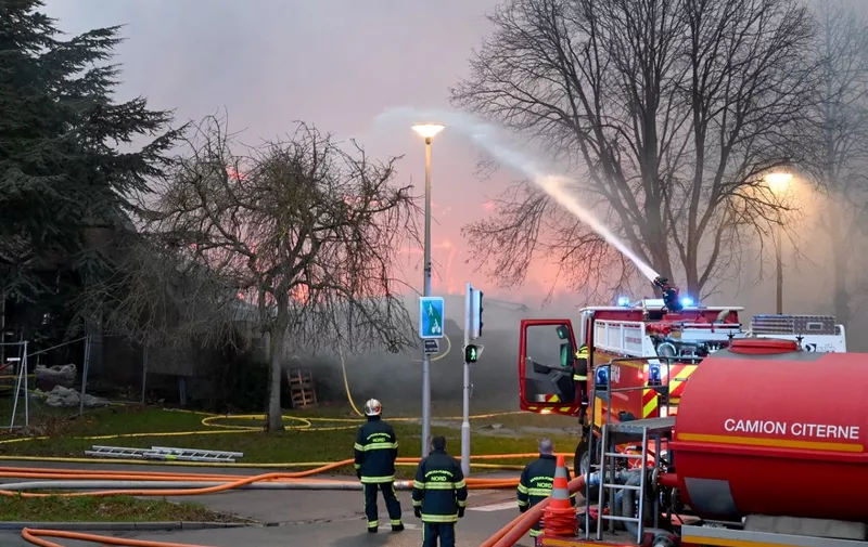 Firefighters spray water on the fire ravaging a sports complex in the Northern French city of Gravelines, damaging most of the site that includes among other equipment a swimming pool and a cafeteria, and totally destroying the arena hosting the games of the French Basketball Elite championship team of Gravelines, on December 25, 2023. (Photo by Bernard BARRON / AFP)