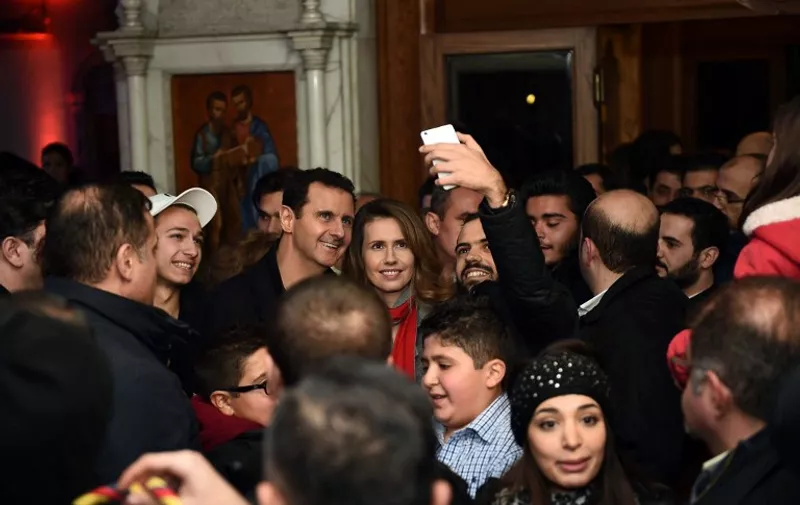 A handout image obtained from the official facebook page of the Syrian Presidency shows Syrian President Bashar al-Assad (C-L) and his wife Asma al-Assad (C-R) posing for a picture with a Syrian man as they attend a Christmas choral presentation at the Lady of Damascus Catholic Church in the Syrian capital on December 18, 2015. AFP PHOTO / HO / THE OFFICIAL FACEBOOK PAGE OF THE SYRIAN PRESIDENCY == RESTRICTED TO EDITORIAL USE - MANDATORY CREDIT "AFP PHOTO / HO / THE OFFICIAL FACEBOOK PAGE OF THE SYRIAN PRESIDENCY" - NO MARKETING NO ADVERTISING CAMPAIGNS - DISTRIBUTED AS A SERVICE TO CLIENTS == / AFP / SYRIAN PRESIDENCY FACEBOOK PAGE / HO