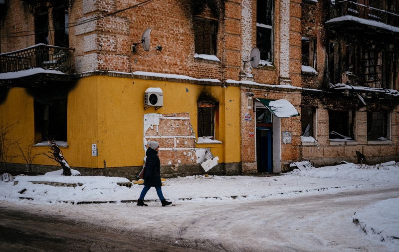A woman walks near a cut off of the wall (C) of a damaged building from where a group people tried to steal a work of the famous British artist Banksy in the town of Gostomel, near Kyiv, on December 3, 2022, amid the Russian invasion of Ukraine. - Ukraine has detained eight people over the theft from a wall in the Kyiv suburbs of a mural painted by elusive British street artist Banksy, the authorities said. "A group of people tried to steal a Banksy mural. They cut out the work from the wall of a house destroyed by the Russians," Kyiv governor Oleksiy Kuleba said in a post on Telegram. (Photo by Dimitar DILKOFF / AFP)