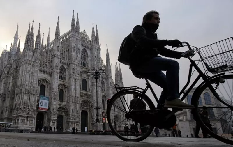 A man rides his bike near the Duomo in Milan on December 28, 2015.
Drivers in Milan will face a limit on daytime travel three days as the northern Italian city tries to bring air pollution down from dangerous levels. A lack of rainfall has led pollution levels to climb in recent weeks, that has prompted the administration of the Lombardy region, of which Milan is the capital, to appeal to localities to cancel traditional New Year fireworks displays to prevent the smog worsening. / AFP / MARCO BERTORELLO