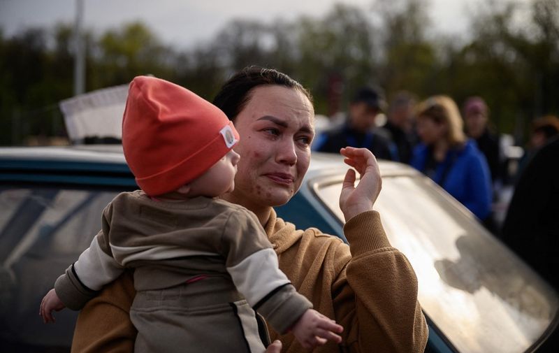 A woman reacts as she holds a child after arriving from a Russian-occupied territory at a registration and processing area for internally displaced people in Zaporizhzhia, in Ukraine, on May 2, 2022. (Photo by Ed JONES / AFP)