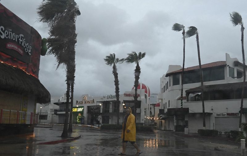 A man walks along a street in Cabo San Lucas, Baja California State, Mexico, as rain and gusts of wind of Hurricane Hilary reach the area, on August 19, 2023. Mexico prepared Friday for a powerful Pacific hurricane that triggered a warning of "potentially catastrophic" flooding in a northwestern tourist region and the neighbouring US state of California. Hurricane Hilary threatened to bring strong winds, flash floods and "life-threatening" surf and rip current conditions, the US National Hurricane Center (NHC) said. (Photo by Alfredo ESTRELLA / AFP)