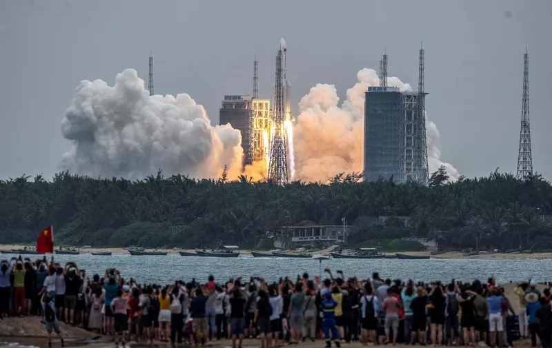 People watch a Long March 5B rocket, carrying China's Tianhe space station core module, as it lifts off from the Wenchang Space Launch Center in southern China's Hainan province on April 29, 2021. (Photo by STR / AFP) / China OUT