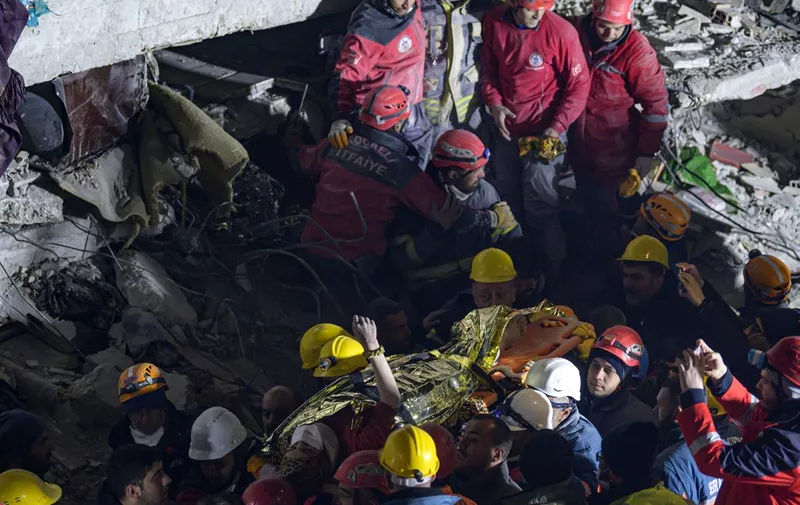 Seher, a 15-year-old Syrian woman raises her arm as she is carried on a stretcher by rescue personnel after being rescued from under the rubble where she was trapped over 210 hours, in Hatay, southeastern Turkey, on February 14, 2023, a week after a deadly earthquake struck parts of Turkey and Syria. (Photo by Yasin AKGUL / AFP)