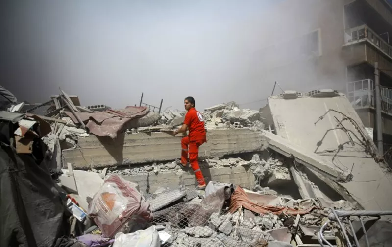 A member of the Syrian Red Crescent inspect rubble searching for victims in the rebel-held area of Douma, east of the capital Damascus, following shelling and air raids by Syrian government forces on August 22, 2015. At  least 20 civilians and wounded or trapped 200 in Douma, a monitoring group said, just six days after regime air strikes killed more than 100 people and sparked international condemnation of one of the bloodiest government attacks in Syria's war.   AFP PHOTO / ABD DOUMANY
