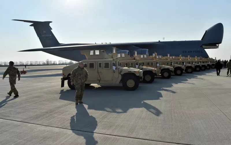 Ukrainian servicemen walk in front of armoured cars at Kiev airport on March 25, 2015 during a welcoming ceremony of the first US plane delivery of non-lethal aid, including 10 Humvee vehicles. American lawmakers voted overwhelmingly on March 24 to urge President Barack Obama to provide Ukraine with lethal weapons to defend itself against Russian "aggression." The US House of Representatives approved the resolution in a broadly bipartisan 348-48 vote, heaping further pressure on the Obama administration to end its delays in providing weapons and other heavy military equipment to Kiev forces.  AFP PHOTO / SERGEI SUPINSKY (Photo by Sergei SUPINSKY / AFP)