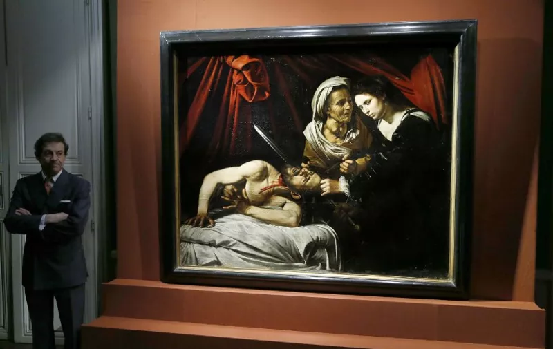 French art expert Eric Turquin stands on April 12, 2016 in Paris in front of the painting entitled "Judith cutting off the head of Holofernes", presented as being painted by Italian artist Caravaggio (1571-1610), while experts are still to determine its authenticity.  
The painting was found out in an attic of a house near Toulouse, southwestern France. / AFP PHOTO / PATRICK KOVARIK