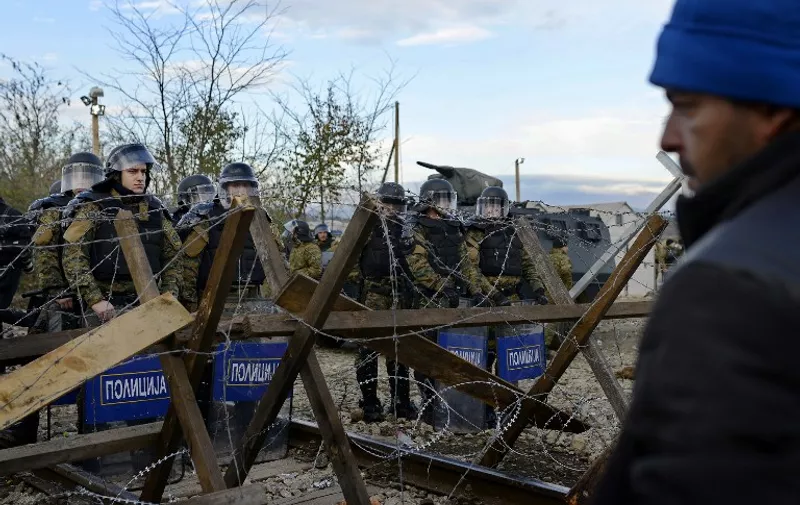 Macedonian police officers stand guard after clashing with migrants on Greek-Macedonia border near Gevgelija on November 28, 2015. A group of migrants trying to enter Macedonia pelted the police with stones on November 28, injuring several officers as the small Balkan country became the latest to build a border fence aimed at checking the flow of newcomers. AFP  PHOTO / ROBERT ATANASOVSKI / AFP / ROBERT ATANASOVSKI