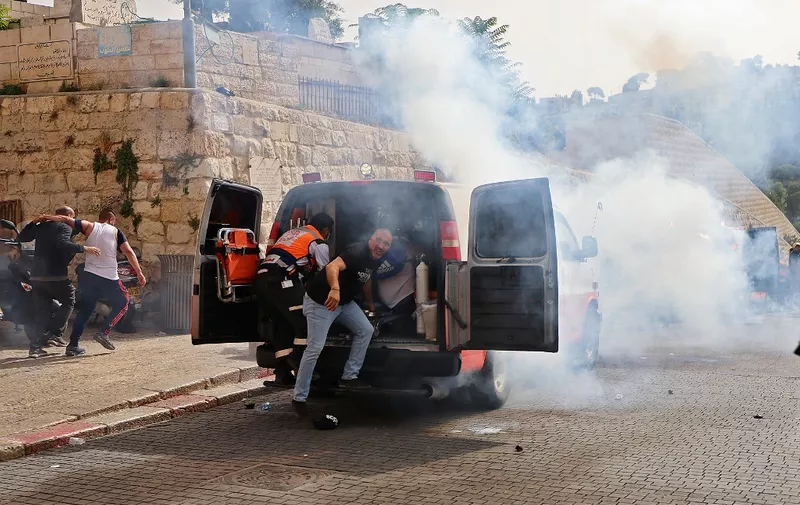 Palestinian medics evacuate wounded protesters as Israeli security forces fire tear gas in Jerusalem's Old City on May 10, 2021, as a planned march marking Israel's 1967 takeover of the holy city threatened to further inflame tensions. (Photo by EMMANUEL DUNAND / AFP)