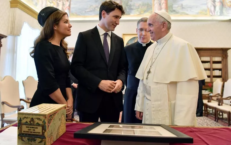 Pope Francis (R) exchanges gifts with Canadian Prime Minister Justin Trudeau (C) and his wife Sophie Gregoire-Trudeau (L) at the end of a private audience at the Vatican on May 29, 2017.  / AFP PHOTO / POOL / Ettore FERRARI