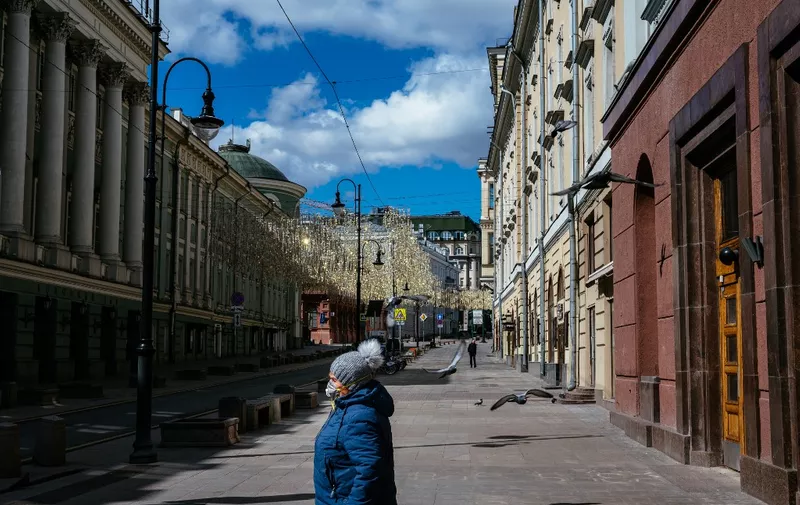 A woman walks down a deserted street in central Moscow on April 21, 2020, during a strict lockdown in Russia to stop the spread of the novel coronavirus COVID-19. (Photo by Dimitar DILKOFF / AFP)