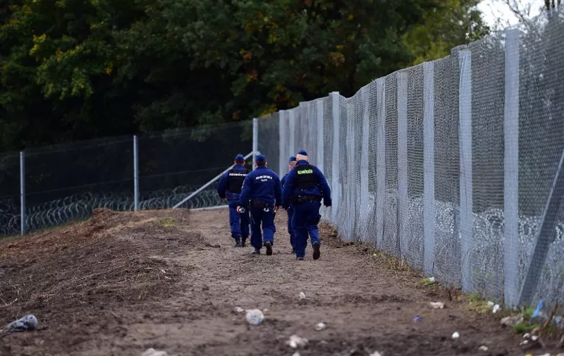 Police officers patrol along a new border fence at the Hungarian-Croatian border near Zakany on October 17, 2015. The border between Hungary and Croatia has been closed to "illegal" migrants, the Hungarian government said, with barbed wire fences being set up to seal the frontier. Croatia announced that it would divert migrants to Slovenia after Hungary said it would close the border with its fellow EU member -- a major transit point for tens of thousands of refugees. AFP PHOTO / ATTILA KISBENEDEK / AFP / ATTILA KISBENEDEK