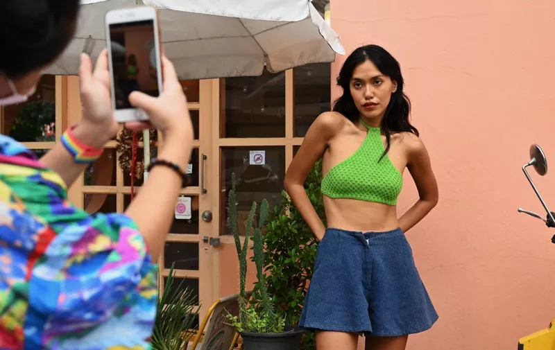 This photo taken on October 20, 2021 shows online influencer Mutchima Friend Wachirakomain having her photo taken outside a cafe in Bangkok. A global phenomenon of fictional characters is blurring the lines between virtual and reality, as it establishes a foothold in the lucrative multi-billion-dollar influencer market, with a burgeoning crop of 'Made in Thailand' virtual influencers promising to stay forever young and on-trend. (Photo by Lillian SUWANRUMPHA / AFP) / To go with 'THAILAND-E-COMMERCE-VIRTUAL-INFLUENCERS,FOCUS' by Dene-Hern CHEN