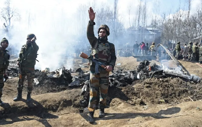 UPDATING CAPTION
Indian soldiers gesture near the remains of an Indian Air Force helicopter after it crashed in Budgam district, outside Srinagar on February 27, 2019. - Officials said an investigation was underway into the cause of the crash, which came as Pakistan claimed to have shot down two Indian fighter jets in the divided and disputed Kashmir region. (Photo by Tauseef MUSTAFA / AFP) / UPDATING CAPTION