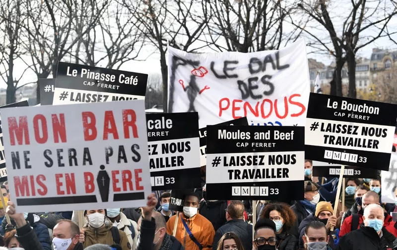 Protesters hold placards on December 14, 2020 in Paris during a demonstration of hotel and restaurant owners  as well as tourism professionals to demand their businesses to reopen amidst the Covid-19 pandemic, caused by the novel coronavirus. The placard (L) reads "my bar will not be placed in a coffin". (Photo by Alain JOCARD / AFP)