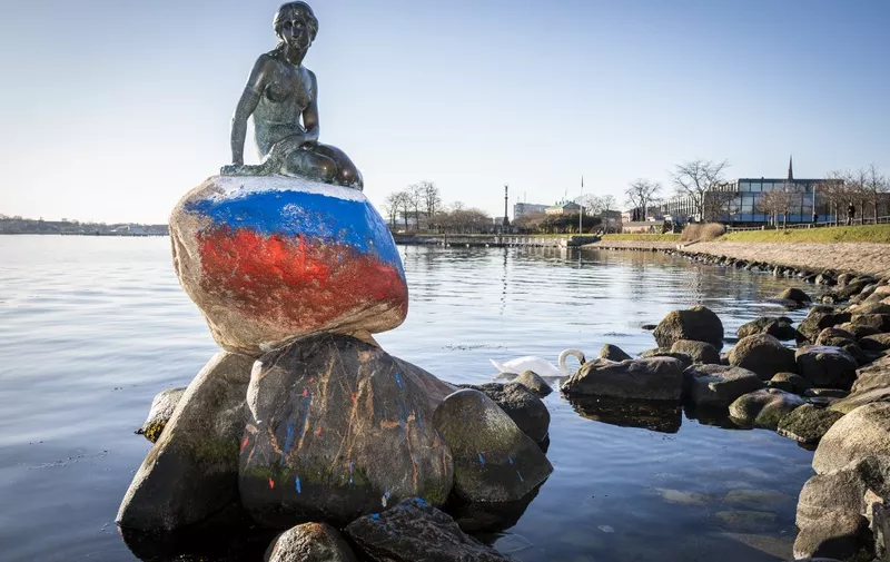 The Little Mermaid sculpture, the emblem of Copenhagen and Denmark, is pictured on March 2, 2023 Copenhagen after it has been vandalised with the Russian flag painted on the stone she sits on. (Photo by Ida Marie Odgaard / Ritzau Scanpix / AFP) / Denmark OUT