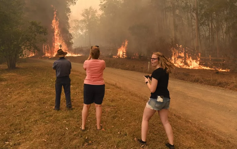 People watch as the fire front approaches their home at Nabiac, some 350kms north of Sydney, on November 15, 2019. - The death toll from devastating bushfires in eastern Australia has risen to four after a man's body was discovered in a scorched area of bushland, police said on November 14. (Photo by WILLIAM WEST / AFP)