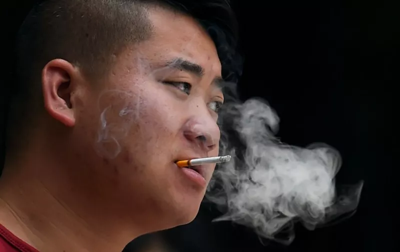 A man smokes a cigarette outside the entrance to a childrens hospital in Beijing on June 1, 2015. The toughest anti-smoking legislation in China's history came into effect on June 1 in Beijing, with unprecedented fines and a hotline to report offenders but fears of weak enforcement.   AFP PHOTO / GREG BAKER