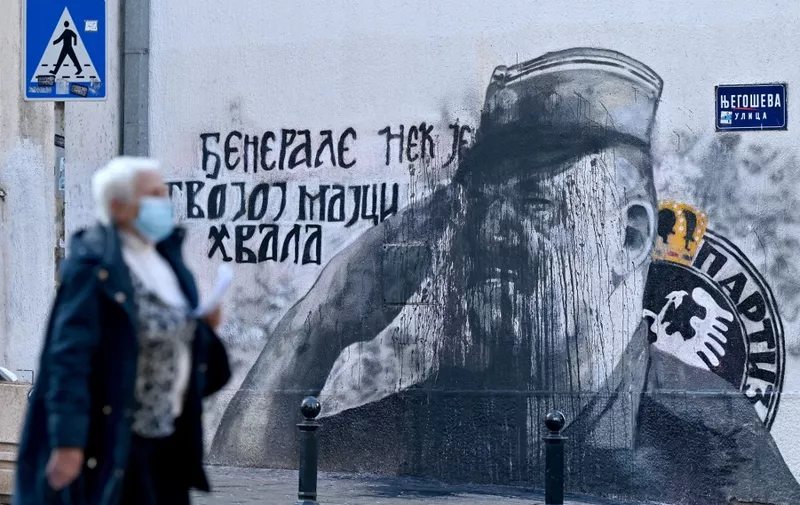 A pedestrian walks past a mural, vandalized with black paint, depicting former Bosnian Serb military chief Ratko Mladic in Belgrade on November 15, 2021. (Photo by Andrej ISAKOVIC / AFP)