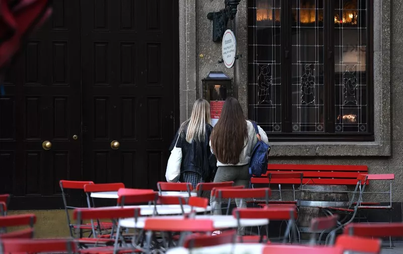 Two girls stand at the closed 'Frueh' beer restaurant on March 17, 2020 in Cologne, western Germany, where restaurants closed, as well as many activities slowed down or came to a halt due to the spread of the novel coronavirus COVID-19. (Photo by Ina FASSBENDER / AFP)