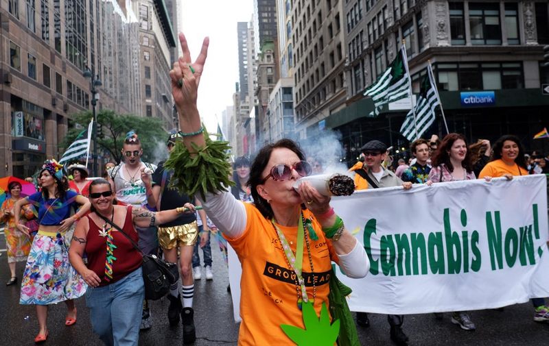 A participant in support of legalizing cannabis gestures during the 2015 New York City Pride march in New York on June 28, 2015. Under a sea of rainbow flags, hundreds of thousands of jubilant supporters poured onto New York's streets for the annual Gay Pride March, two days after the US Supreme Court's landmark ruling to legalize gay marriage. AFP PHOTO/JEWEL SAMAD (Photo by JEWEL SAMAD / AFP)