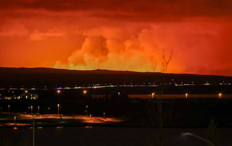 The sky is coloured orange as molten lava flows out from a fissure on the Reykjanes peninsula north of the evacuated town of Grindavik, western Iceland on March 16, 2024. Lava spewed Saturday from a new volcanic fissure on Iceland's Reykjanes peninsula, the fourth eruption to hit the area since December, authorities said. (Photo by Halldor KOLBEINS / AFP)